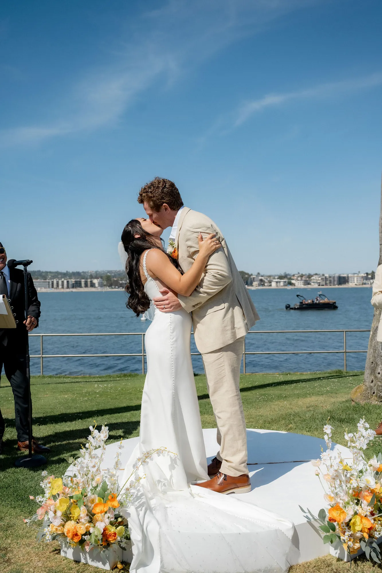 Bride and groom share their first kiss at a waterfront San Diego wedding ceremony